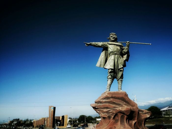 Low angle view of chacho penaloza statue against clear blue sky