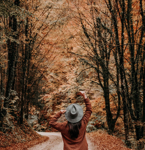 Young woman from behind on road in autumn, fall, forest.