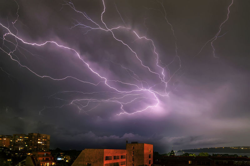 Lightning over illuminated buildings in city at night