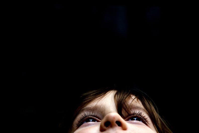 Close-up portrait of young woman against black background