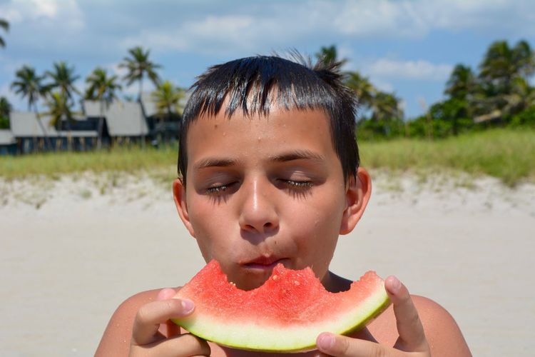 Close-up of boy eating watermelon at beach