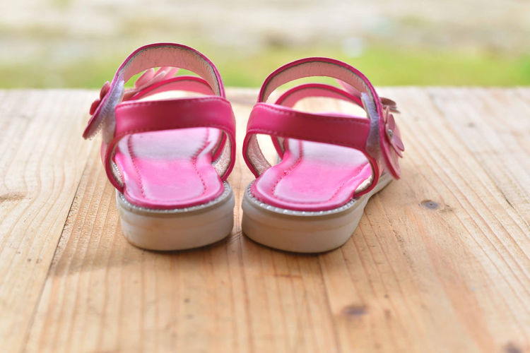 Close-up of pink sandals on wooden table