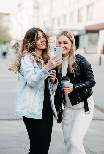 Two girls take a selfie on the street. youth fashion and culture. long hair. smile