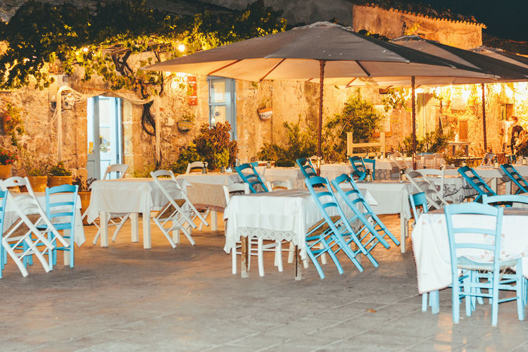 Empty chairs and tables in restaurant against buildings