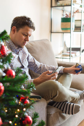 Man sitting by christmas tree at home
