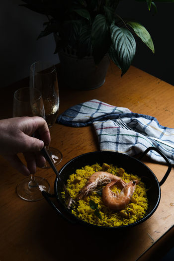 A plate of spanish paella prepared for two accompanied by two glasses
