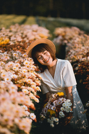 Smiling woman standing by flowering plants on field