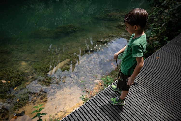 High angle view of boy standing on pier by lake
