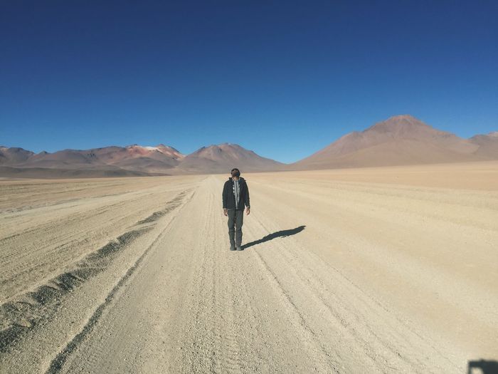 Man standing on desert against clear blue sky
