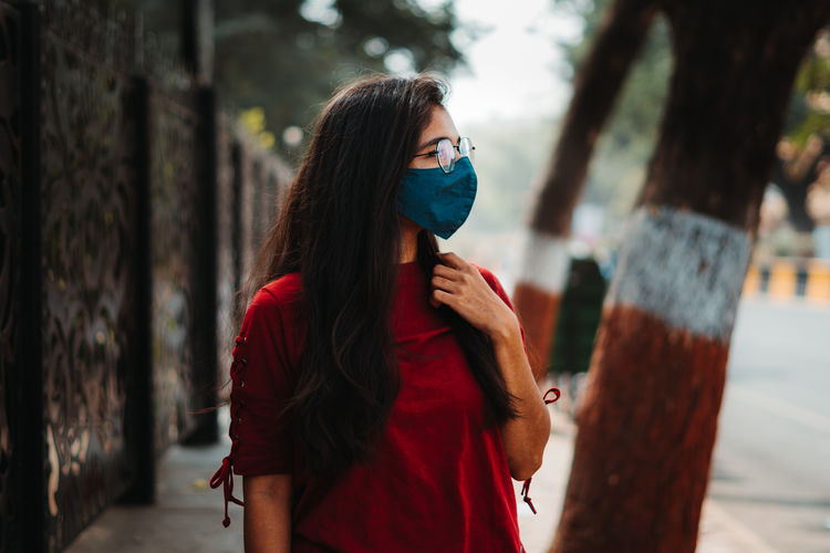 Indian young woman wearing mask and standing at street. during corona virus pandemic