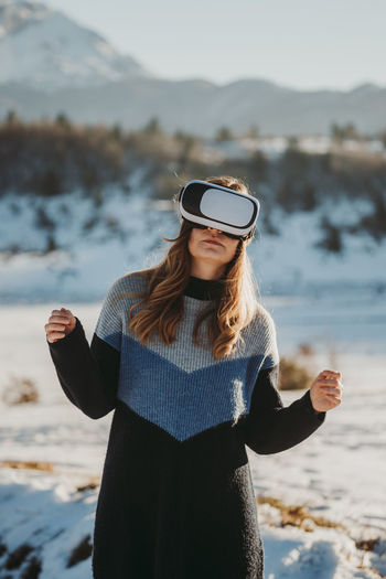 Young woman wearing virtual reality simulator on snow covered land