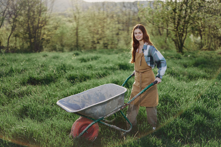 Portrait of young farmer with wheelbarrow in farm