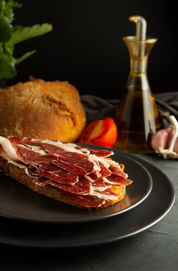 Toasted bread with iberian ham on black plates and rustic background
