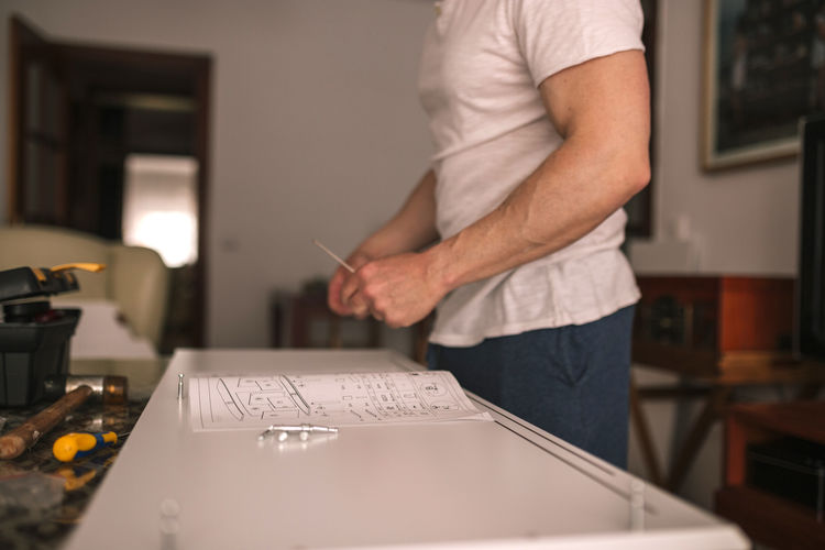Man in his house assembling a table