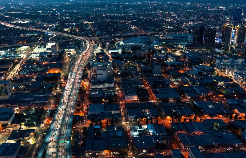 Aerial view of illuminated highway amidst buildings in city at night