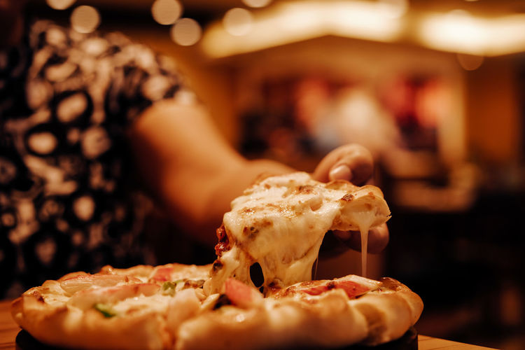 Cropped hand of woman eating pizza
