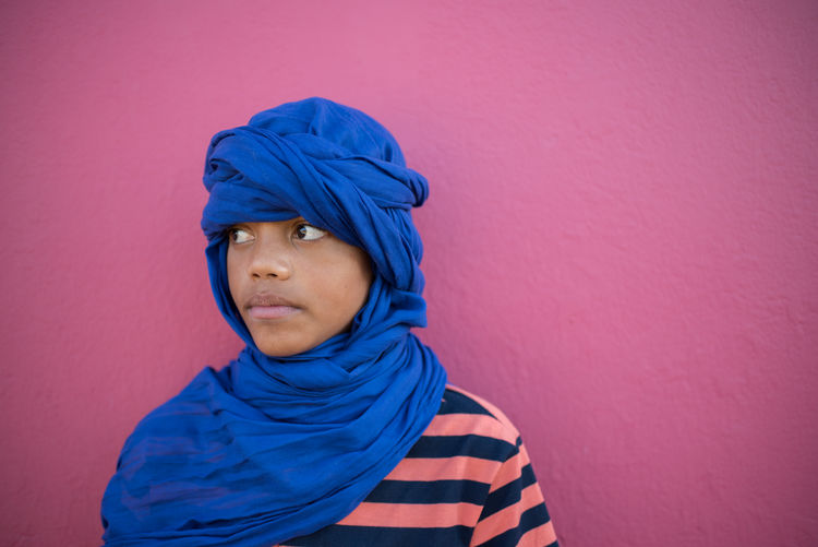 Teenage boy wearing headscarf while standing against wall