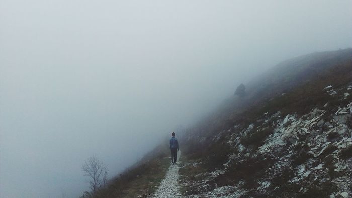 Rear view of man standing on fog covered mountain