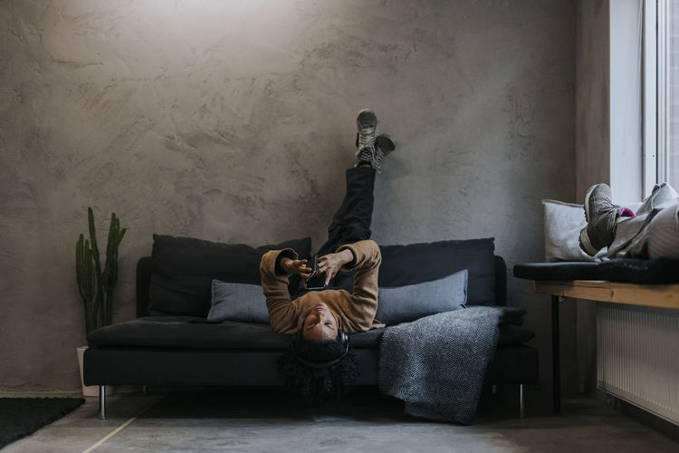 Side view of woman sitting on sofa at home