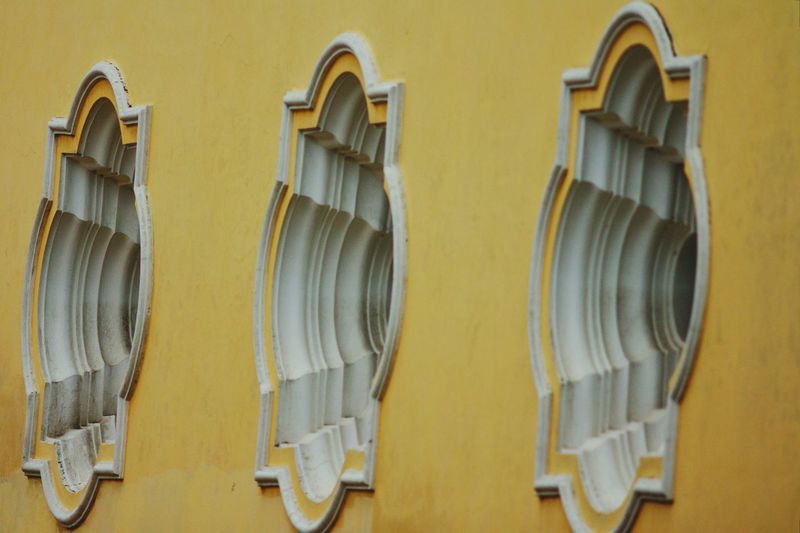 Close-up of three windows on a yellow building