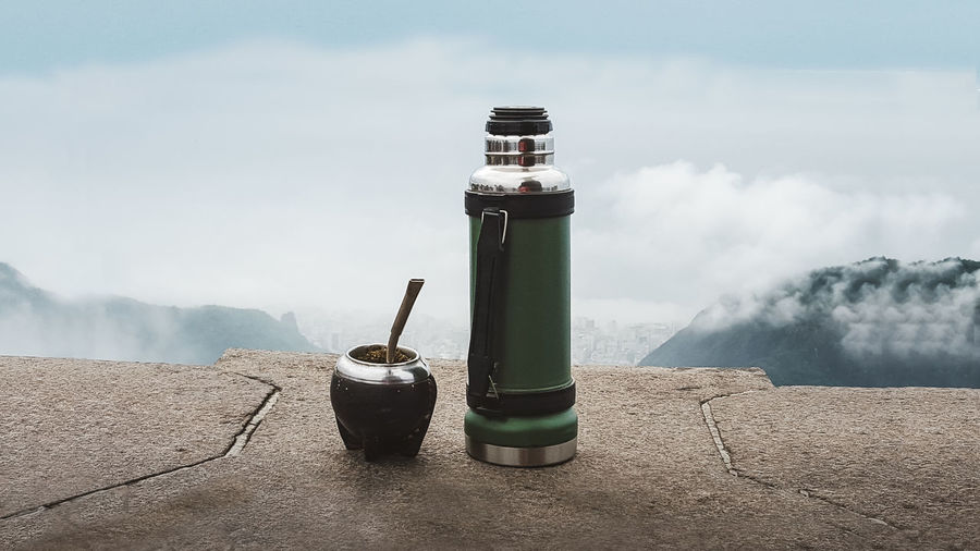 Close-up of water bottle on mountain against sky