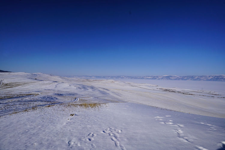 Scenic view of snow covered land against clear blue sky