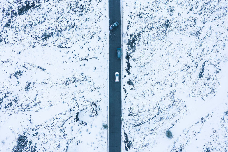 Aerial view of road amidst snow covered fields