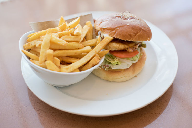 Close-up of chicken burger and french fries in plate on table