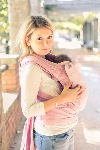 Portrait of woman carrying baby girl outdoors