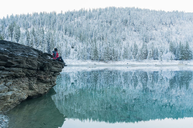 Woman on rock by river against mountain