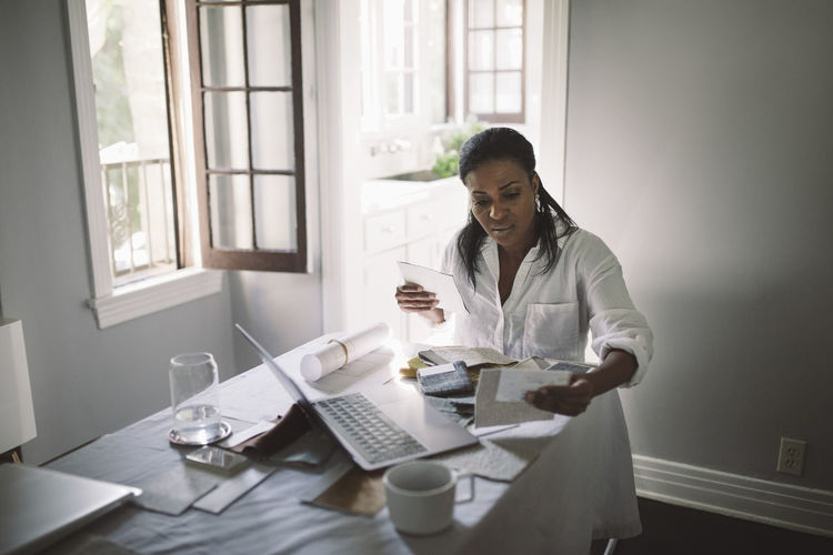 Female entrepreneur working while sitting by dining table at home office