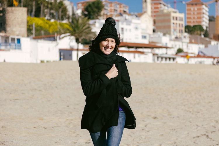Middle-aged woman running happily along the beach on a sunny winter day