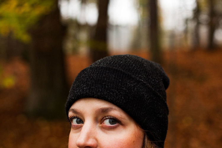Close-up portrait of young woman wearing knit hat at forest