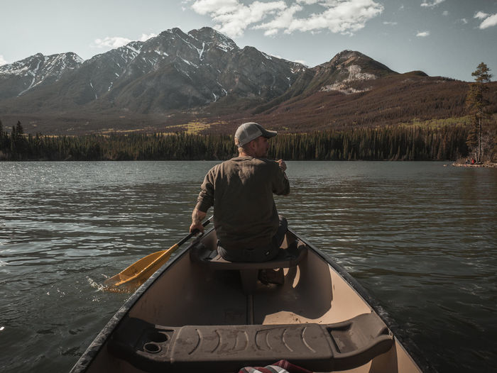 Rear view of man paddling boat in lake