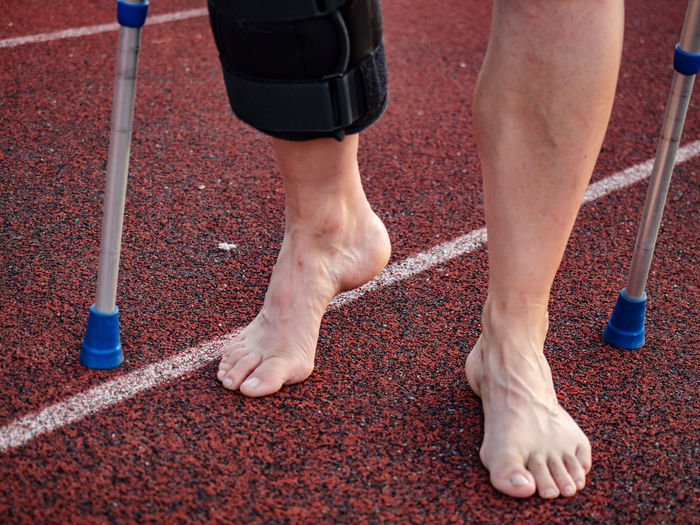Walk by crutches. woman runner got sports injury running on stadium trail