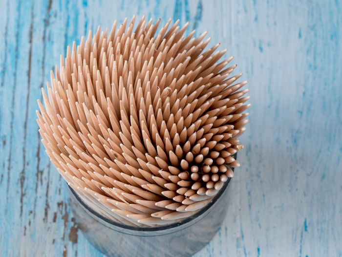 High angle close-up of toothpicks in container on wooden table
