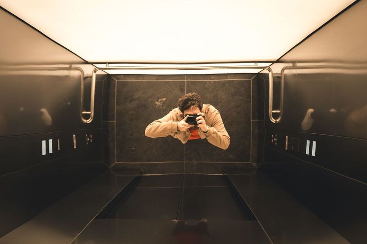 Directly above shot of man photographing with camera in elevator