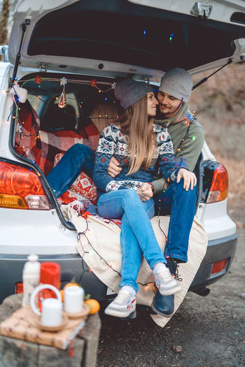 Smiling couple embracing while sitting in car trunk