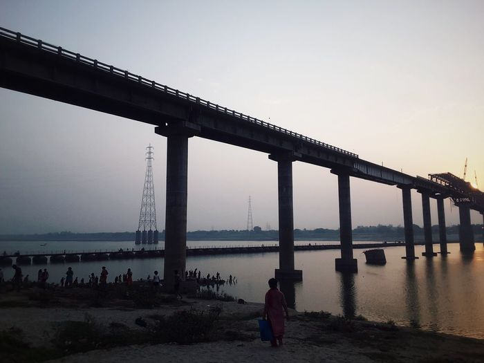 Woman on bridge over river against clear sky
