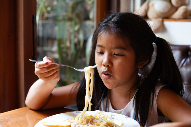 Girl having pasta at table