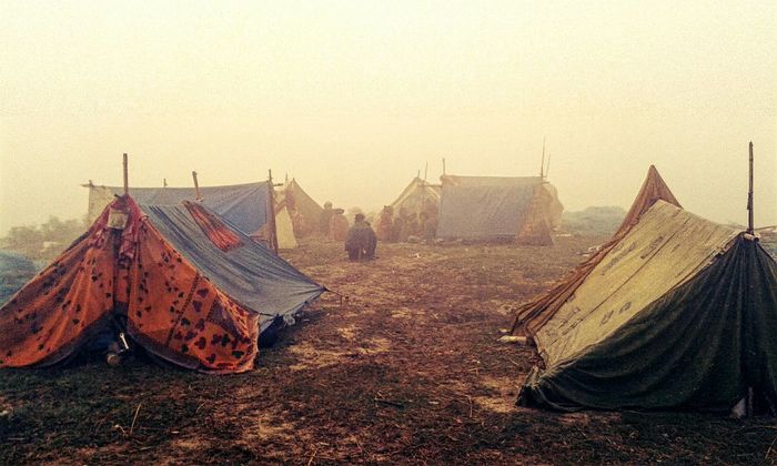 People on field by tents against clear sky during foggy weather