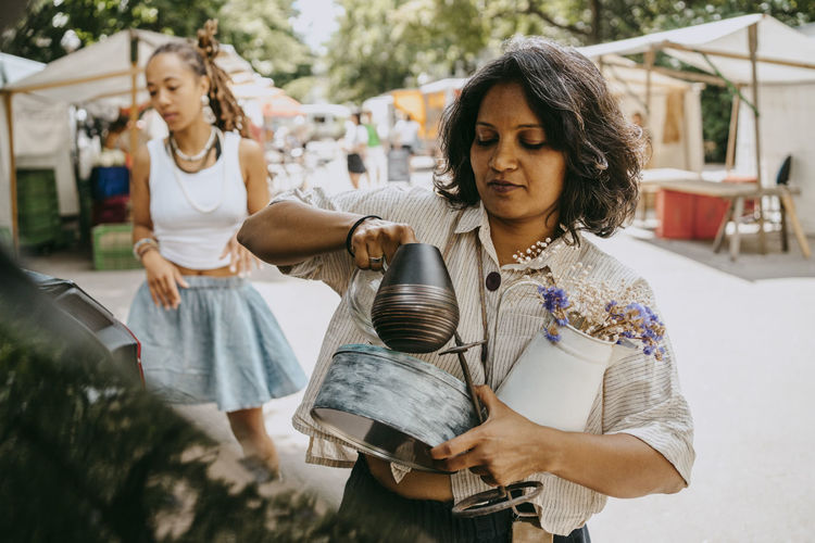 Woman carrying variety of objects while shopping at flea market