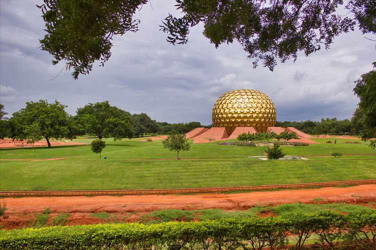 Scenic view of field against cloudy sky in auroville town