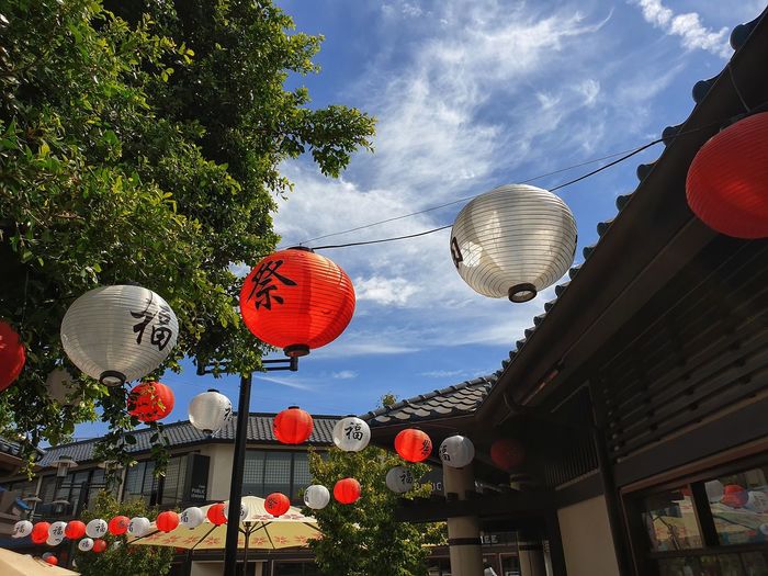 Low angle view of lanterns hanging on street against sky