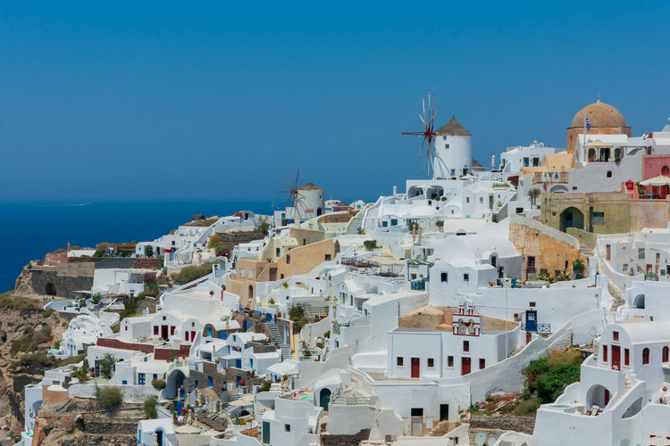 Amazing panoramic view of some white houses of the village of touristic oia in santorini island in aegean sea. the windmill is at the top of the village and the sea at the background. horizon