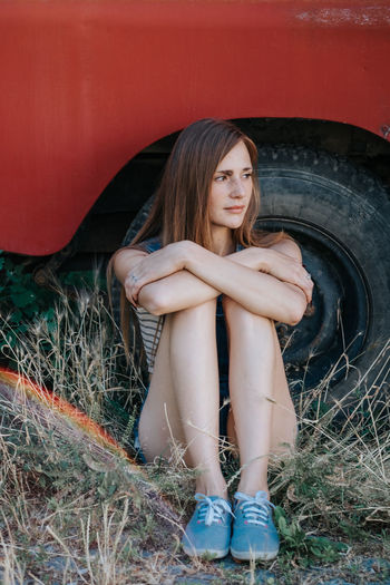 Young woman sitting against tire