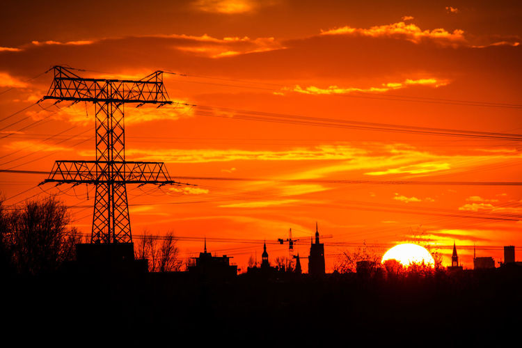 Low angle view of silhouette electricity pylon against romantic sky