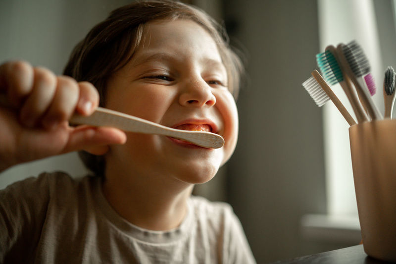 The boy brushes his teeth with a toothbrush made of ecological material