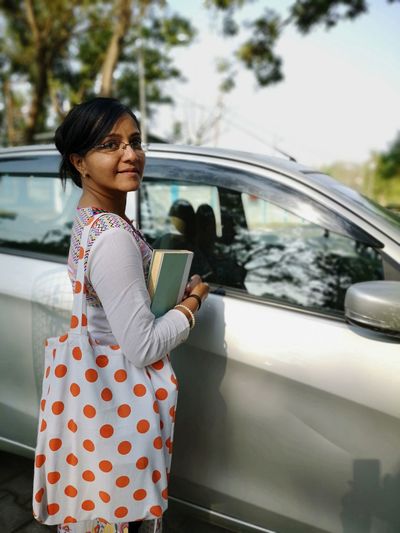 Portrait of woman standing by car in city