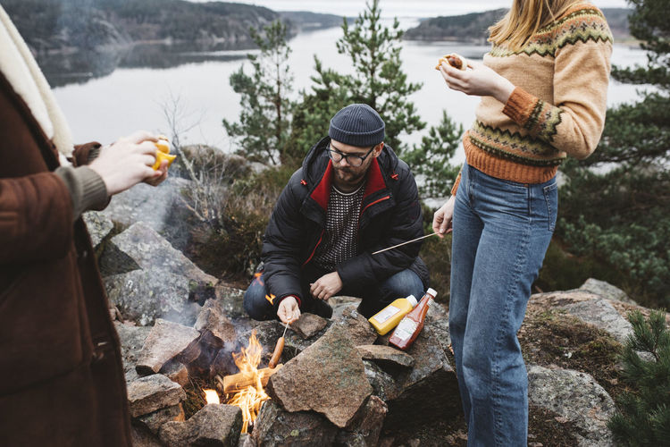 Friends preparing hotdogs over campfire